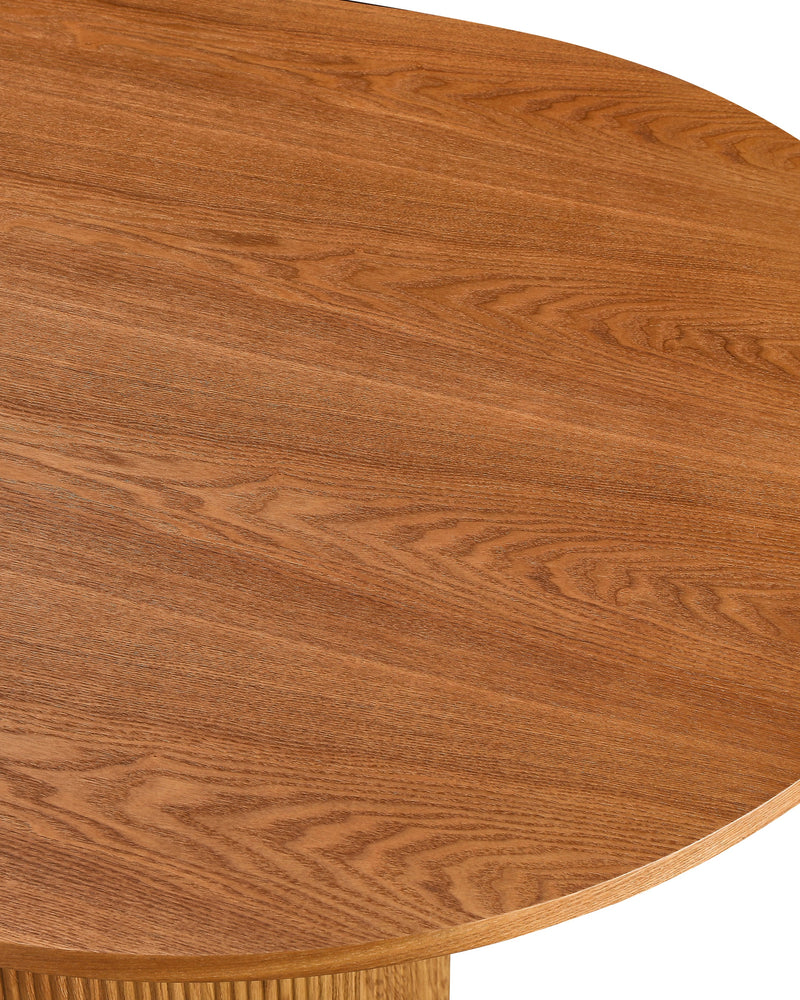Close-up of the tabletop edge and fluted base on the Cydra Dining Table in Caramel Oak