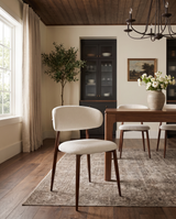 Bouclé Mabel Dining Chair with Walnut-finish metal legs, single chair beside a walnut dining table in a sunlit dining room