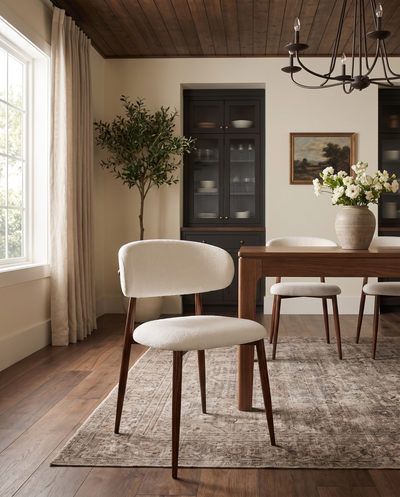 Bouclé Mabel Dining Chair with Walnut-finish metal legs, single chair beside a walnut dining table in a sunlit dining room
